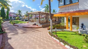 A resort with a paved walkway, outdoor seating areas, and palm trees.
