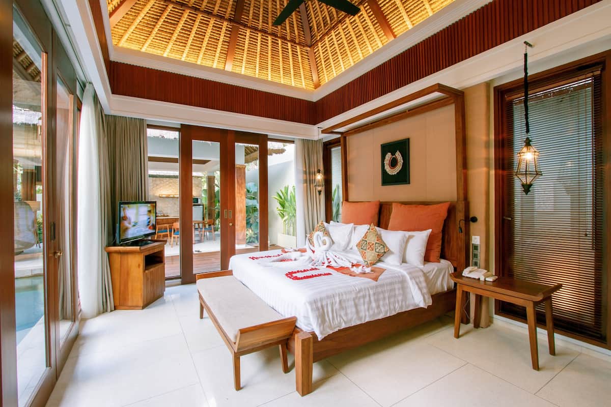 A spacious bedroom with a large bed, wooden headboard, and a ceiling fan.