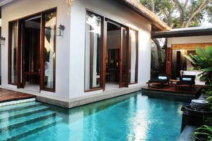 Una casa moderna con piscina, puertas de cristal grandes y terraza de madera.