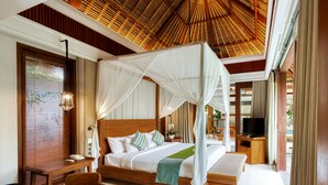 A spacious bedroom with a canopy bed, a television, and a dining area. - Regali Villa (Canggu)