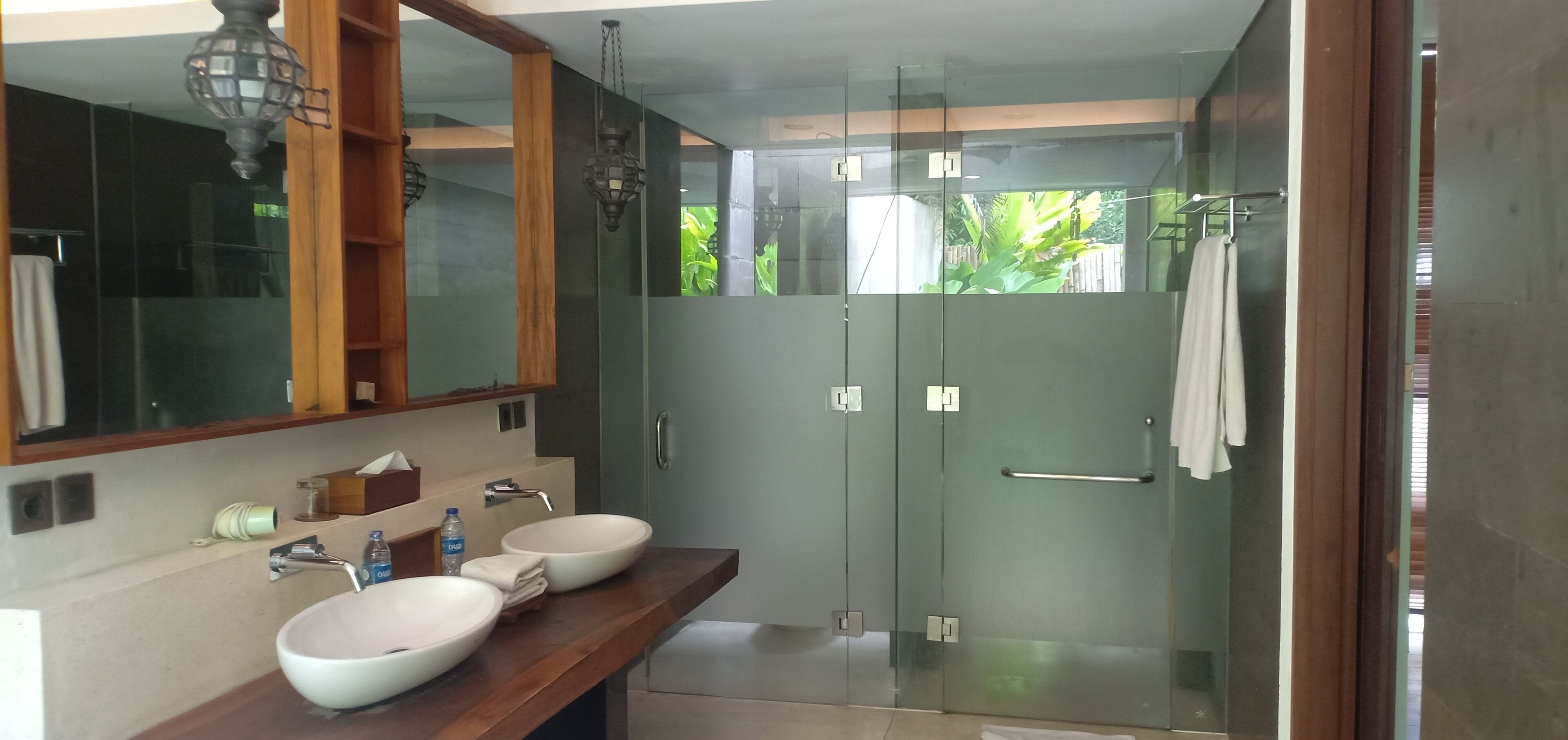 Un baño moderno con dos lavamanos, un espejo grande y cabina de ducha de vidrio.