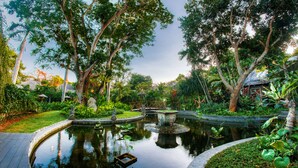 A serene garden with a pond, surrounded by lush greenery and trees. - Regali Villa (Canggu)