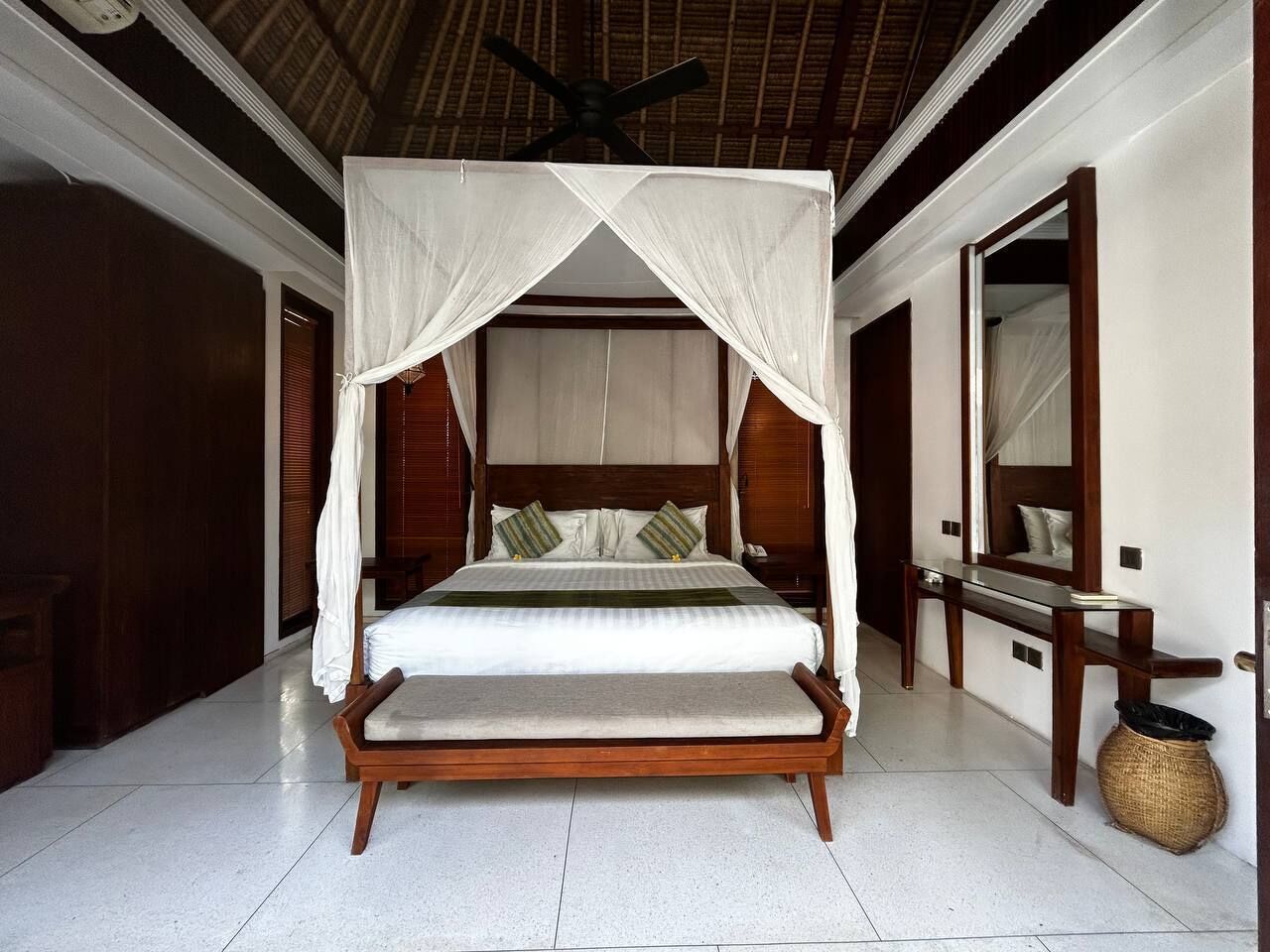A spacious bedroom with a large bed, wooden headboard, and a ceiling fan.