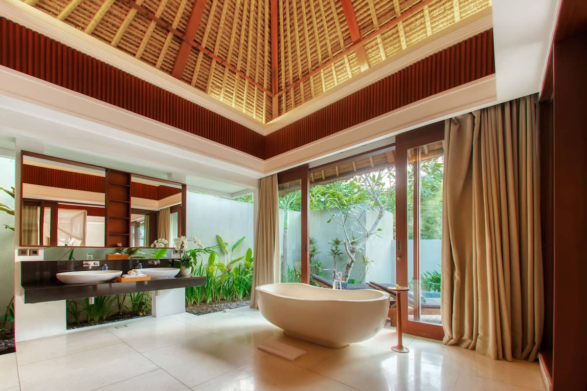 A modern bathroom with a large bathtub, a double sink vanity, and a large mirror.