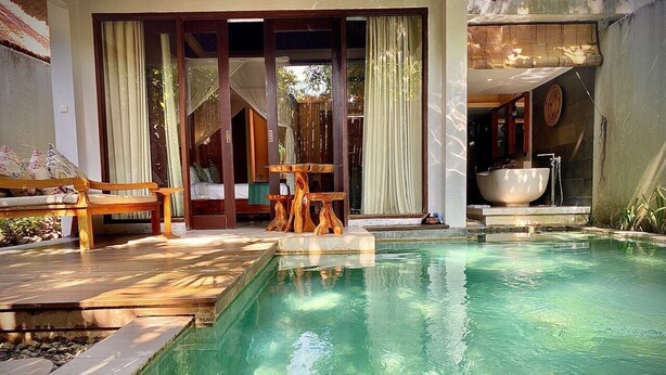 A swimming pool with a wooden deck and a large bowl-shaped sink. - Regali Villa (Canggu)