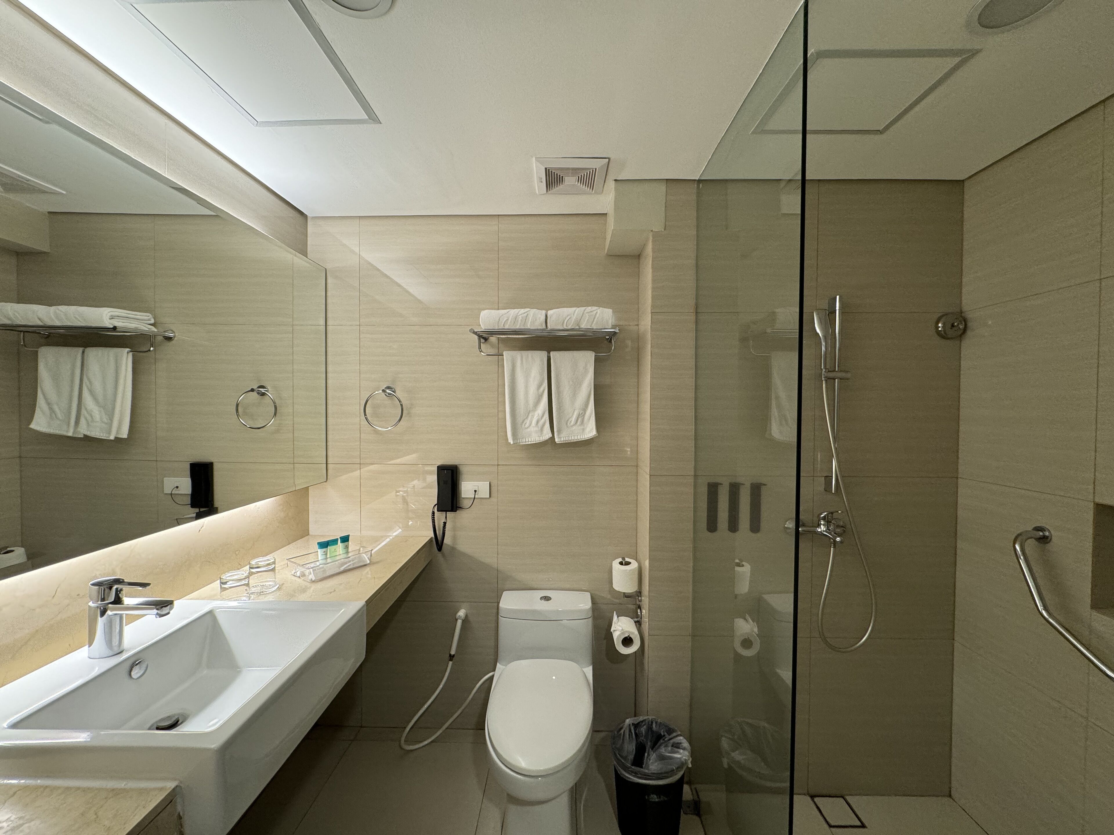 Un baño moderno con un lavamanos grande, inodoro y ducha con mampara de vidrio.