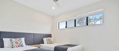 Une chambre d’hôtel avec deux lits, une fenêtre donnant sur un beau paysage et un ventilateur de plafond.