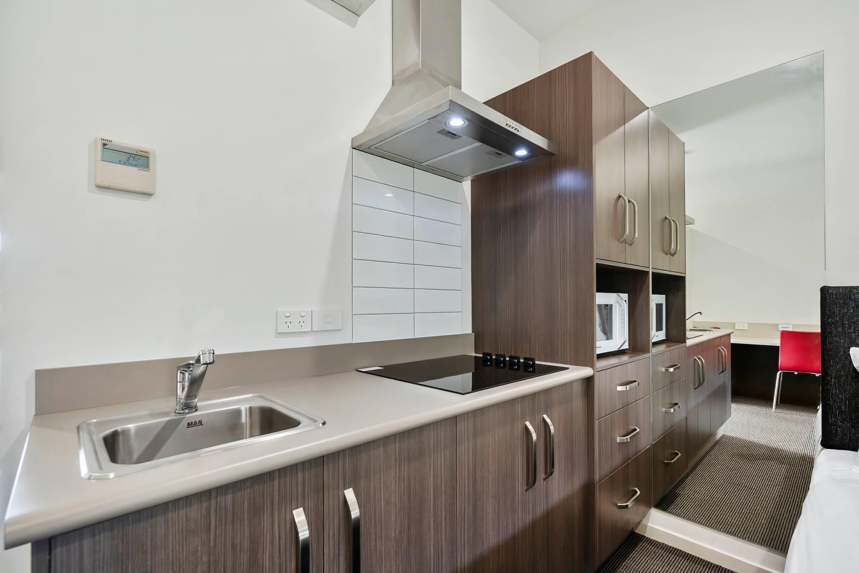 A modern kitchen with a stainless steel sink, a built-in microwave, and wooden cabinets.