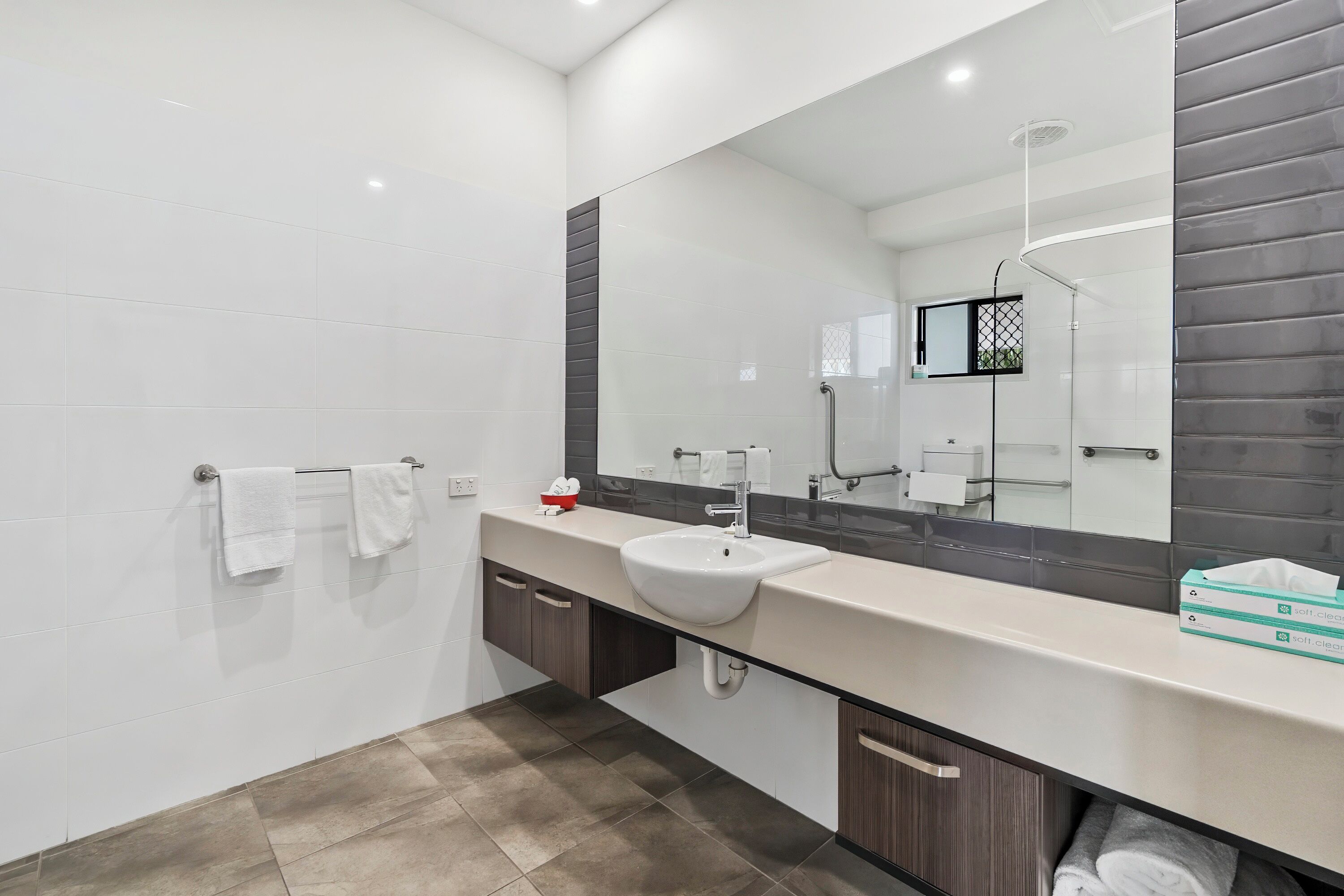 Un baño moderno con un espejo grande, un lavabo y un perchero para toallas.