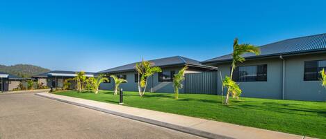 A row of modern buildings with a well-maintained lawn and a clear blue sky.