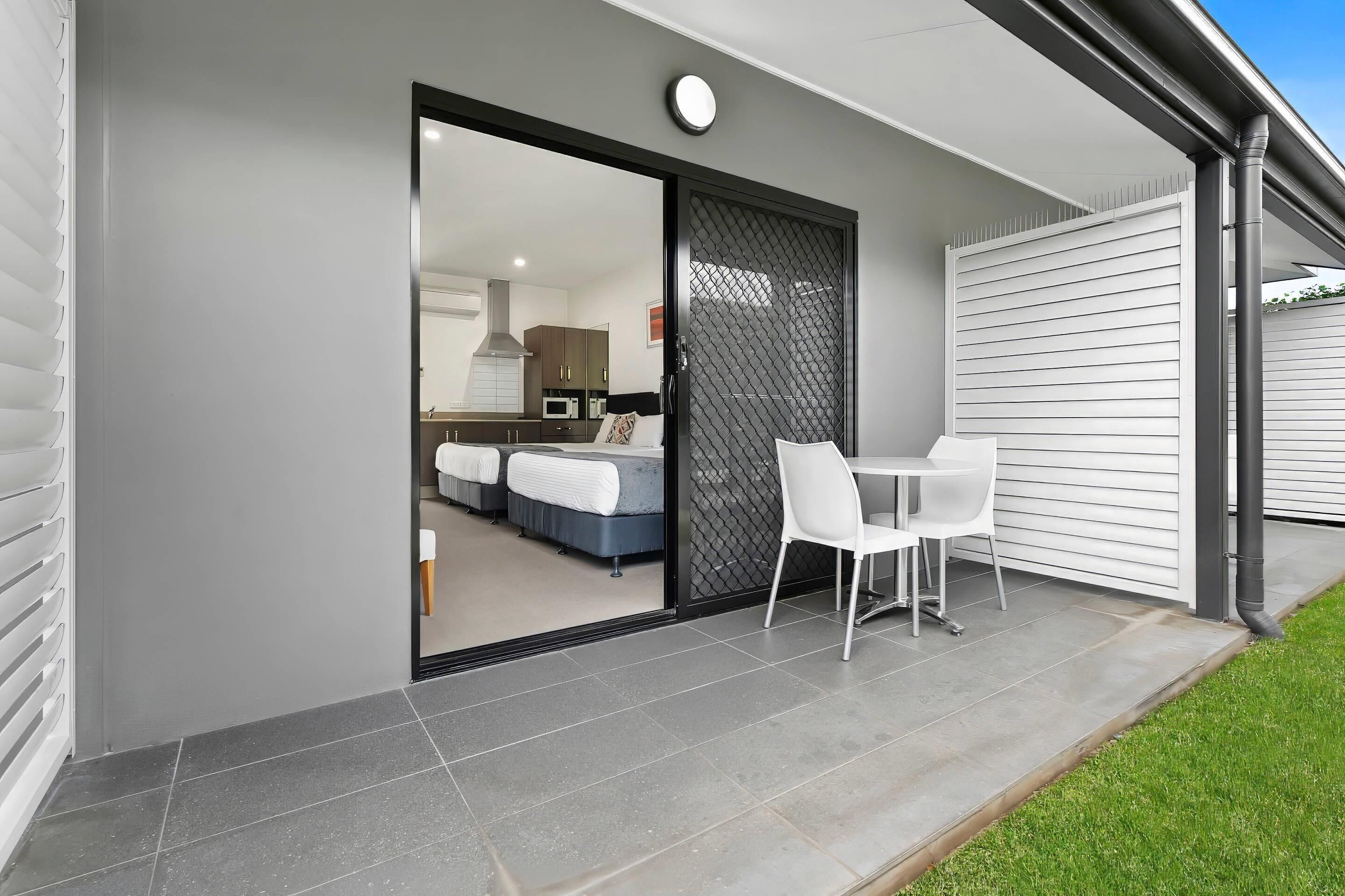 A modern house with a sliding glass door leading to a bedroom with a bed and a desk.