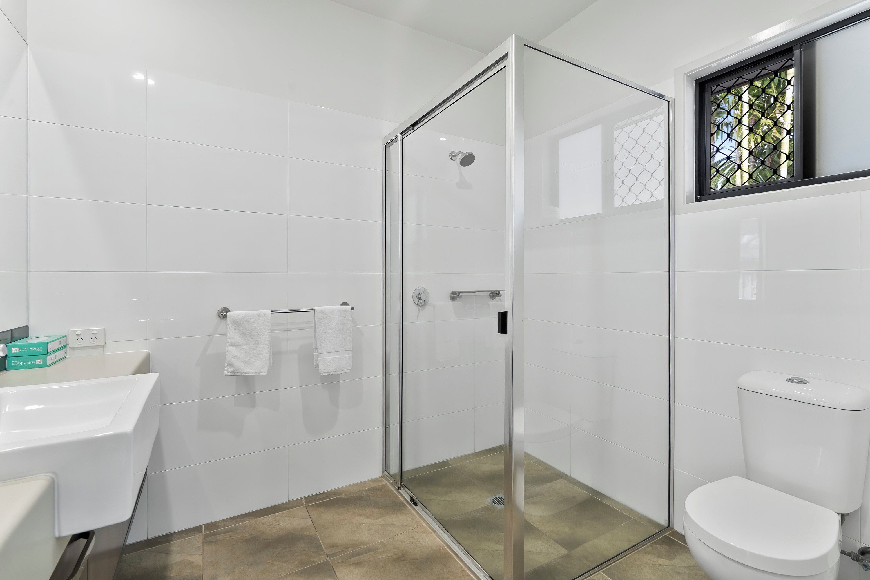 A modern bathroom with a glass shower enclosure, a white sink, and a toilet.
