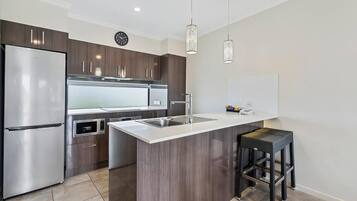 A modern kitchen with a stainless steel refrigerator, a microwave, and a sink.