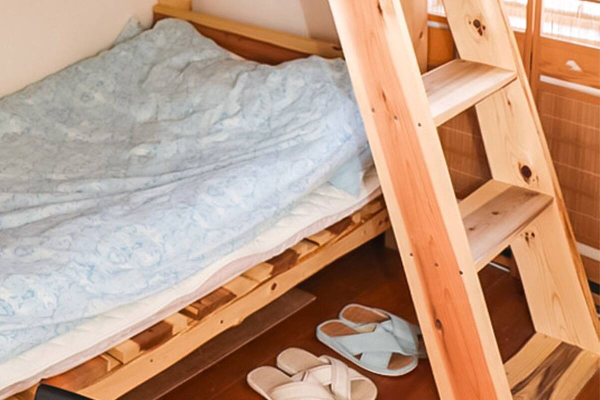 A small, single-bed room with a wooden frame and a mattress.