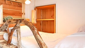Ein Schlafzimmer mit Holz-Kopfteil, einem Bett mit weißer Bettwäsche, einem Holzschrank und einer kleinen Pflanze auf einem Nachttisch.