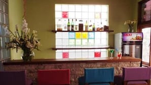 A bar area with a stone counter, multiple bar stools, and a refrigerator.