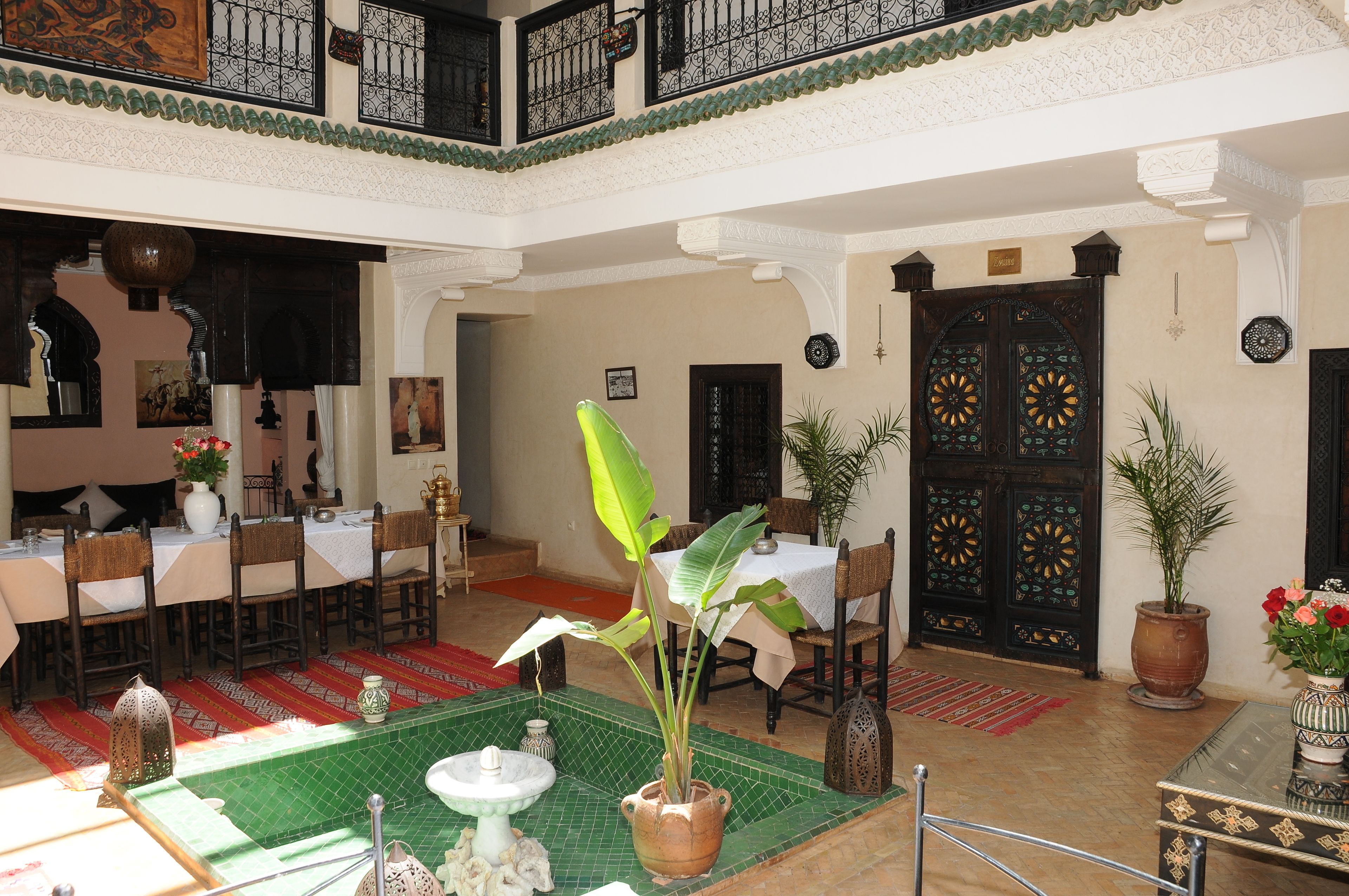 A spacious indoor area with multiple dining tables and chairs, a central fountain, and decorative plants.