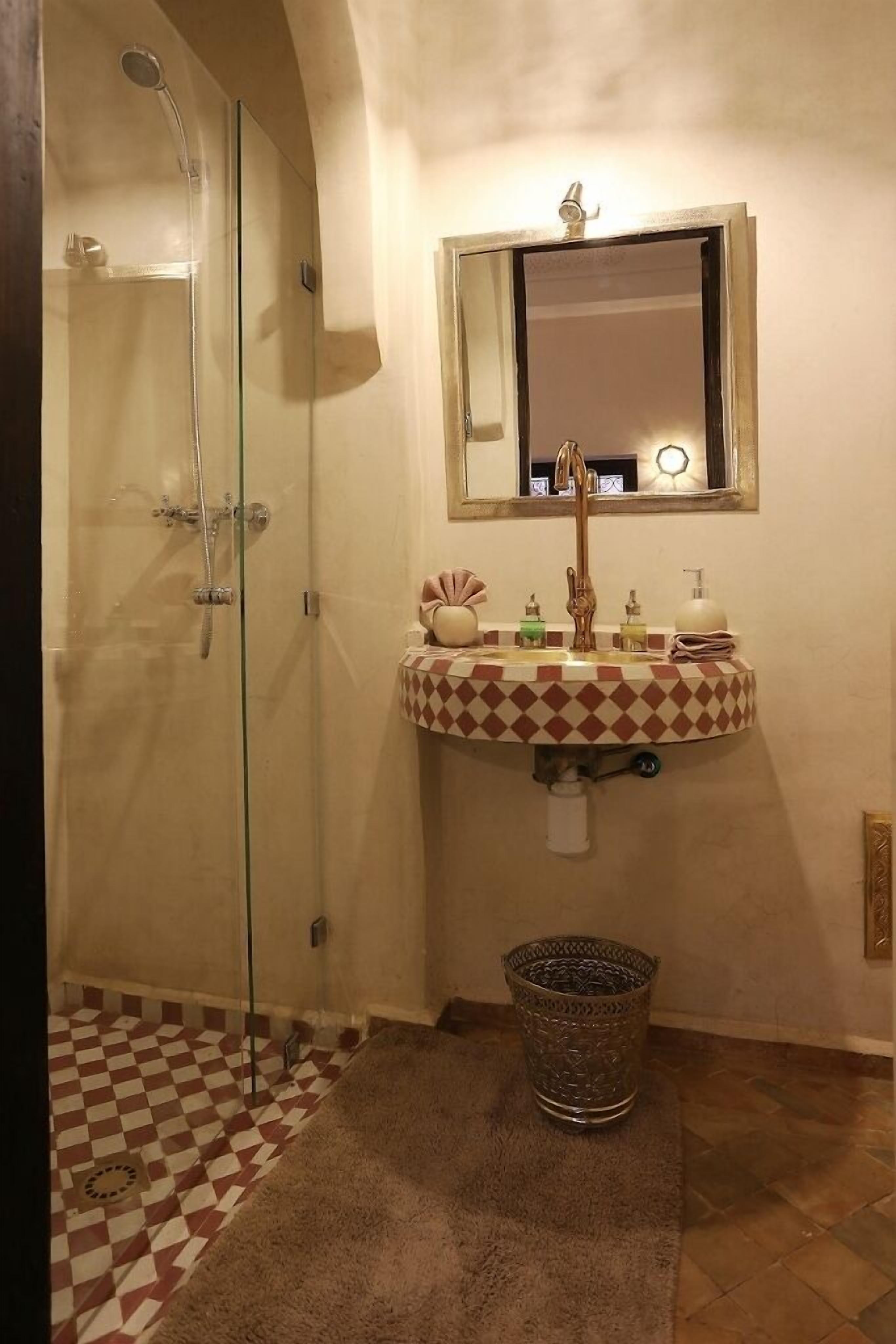 A bathroom with a glass-enclosed shower, a sink with a patterned basin, and a mirror above the sink.