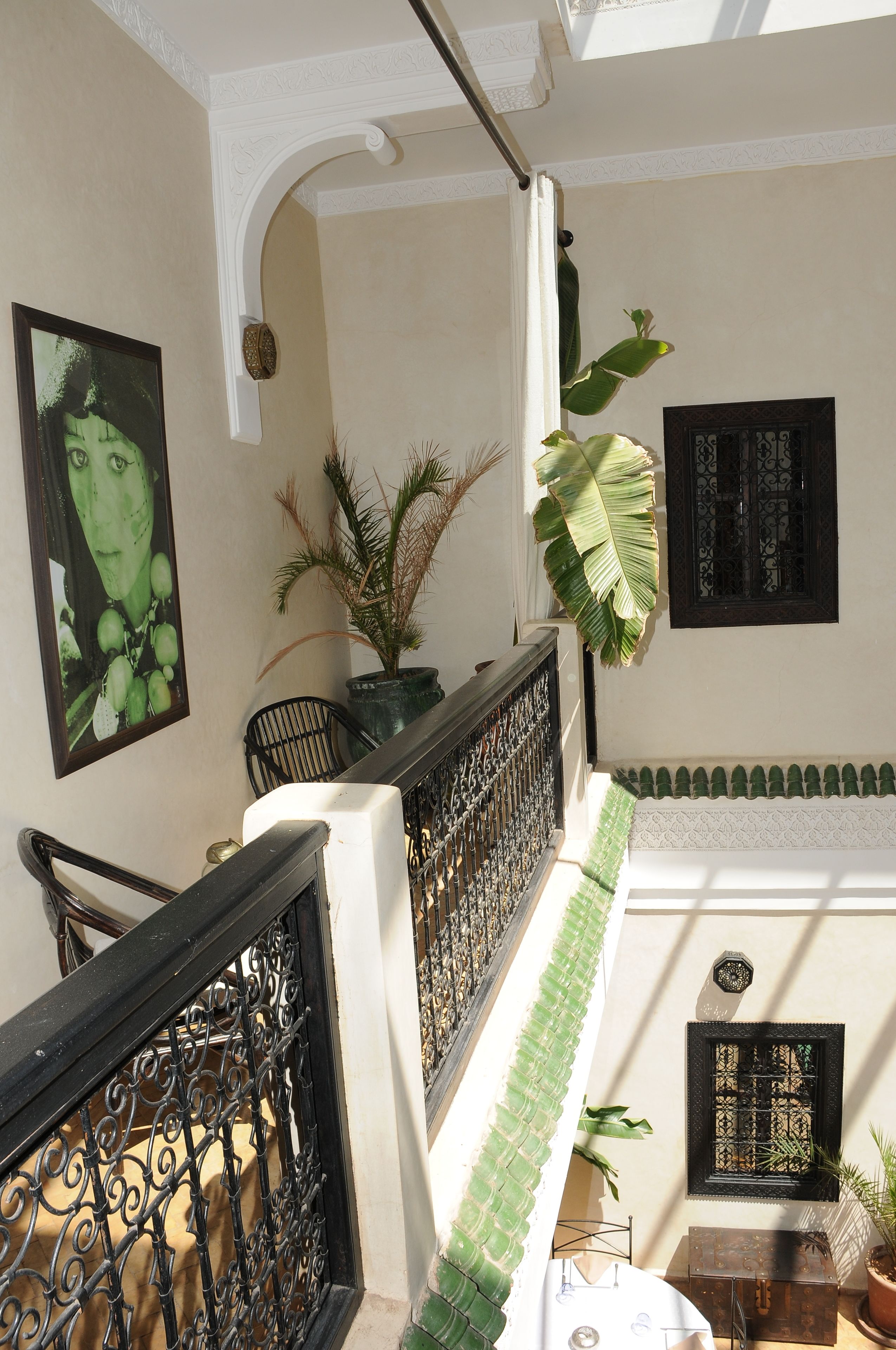 Una escalera con barandilla negra, una planta en maceta y un cuadro en la pared.