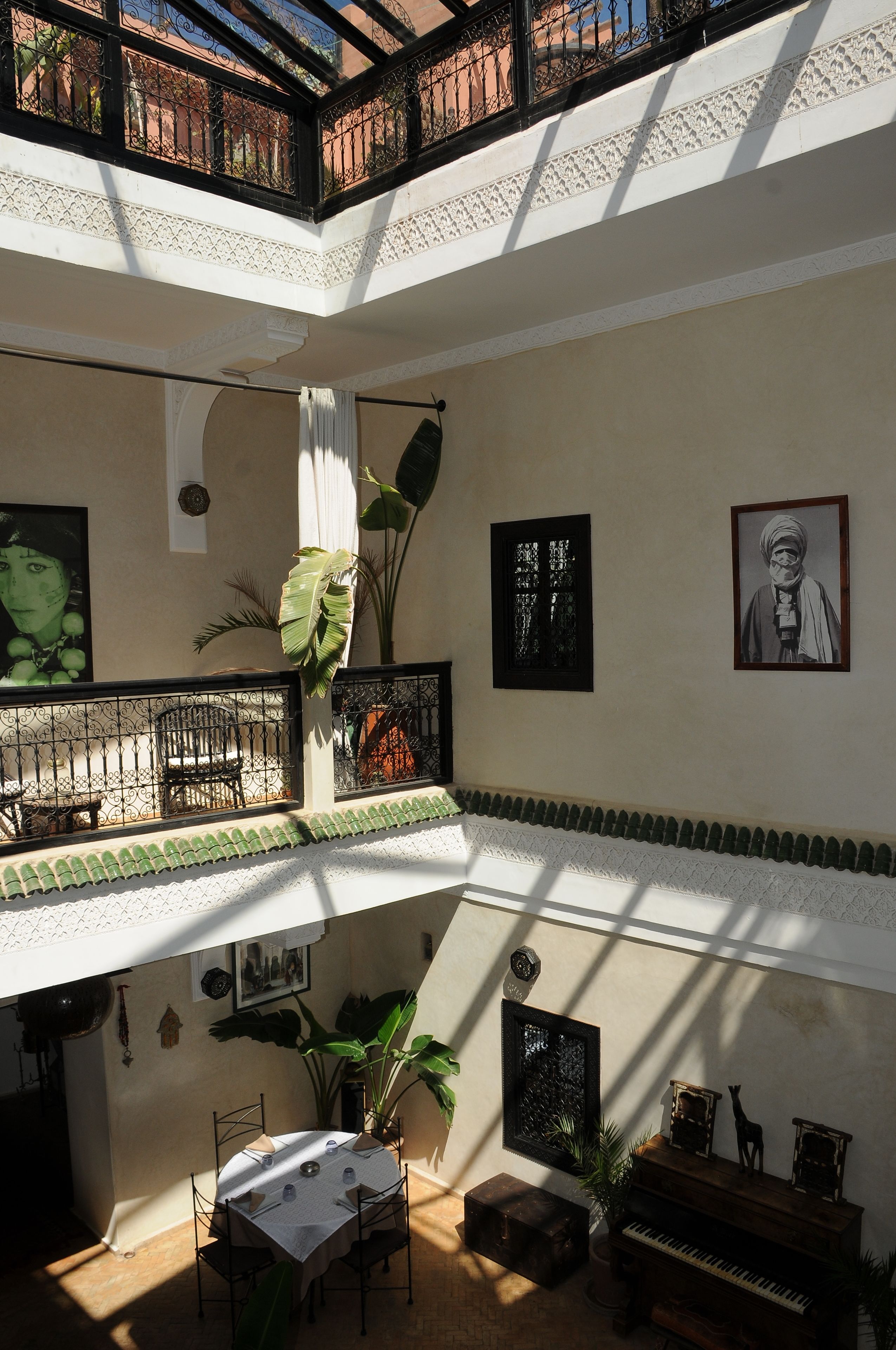 A multi-level atrium with a dining area, potted plants, and artwork on the walls.