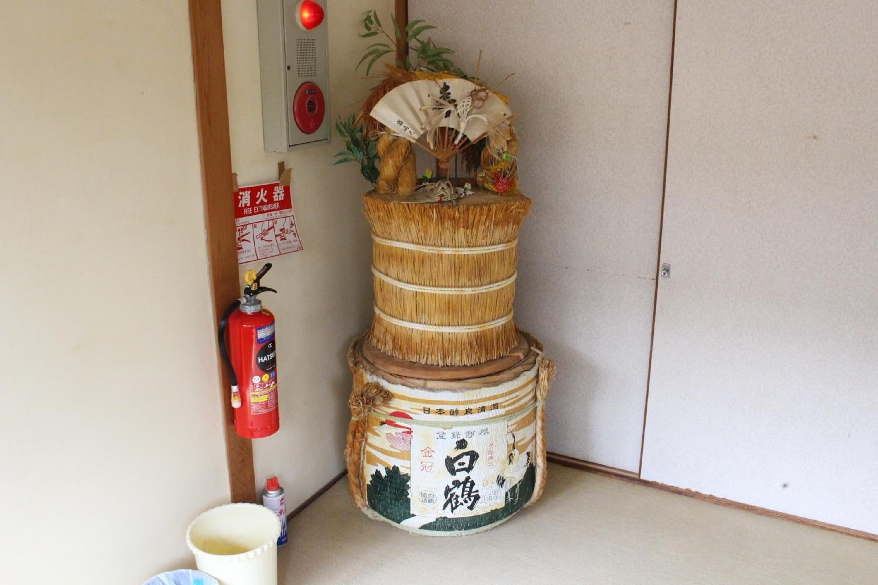 Ein traditioneller japanischer Raum mit Tatami-Boden, einer Shoji-Schiebetür und einem Feuerlöscher an der Wand.