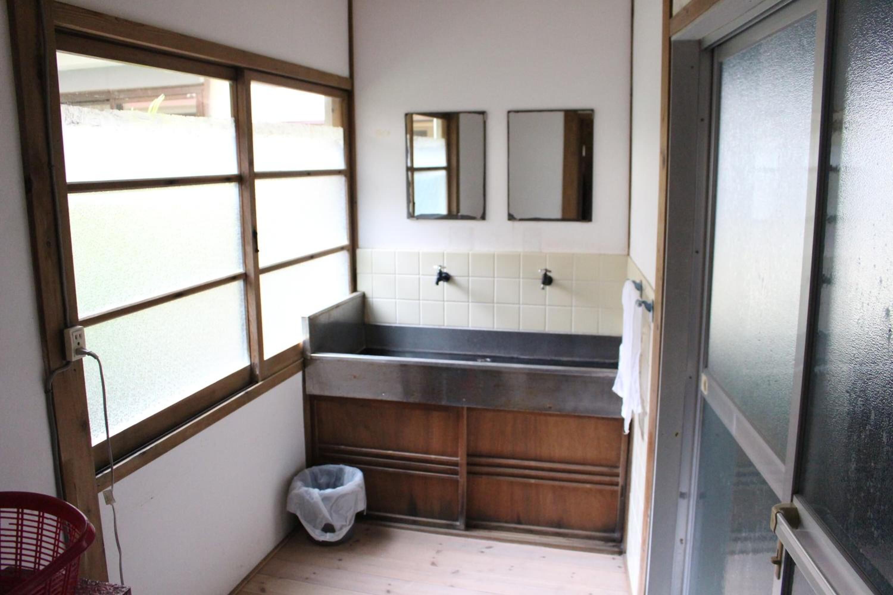 A small bathroom with a window, a sink, and a mirror.