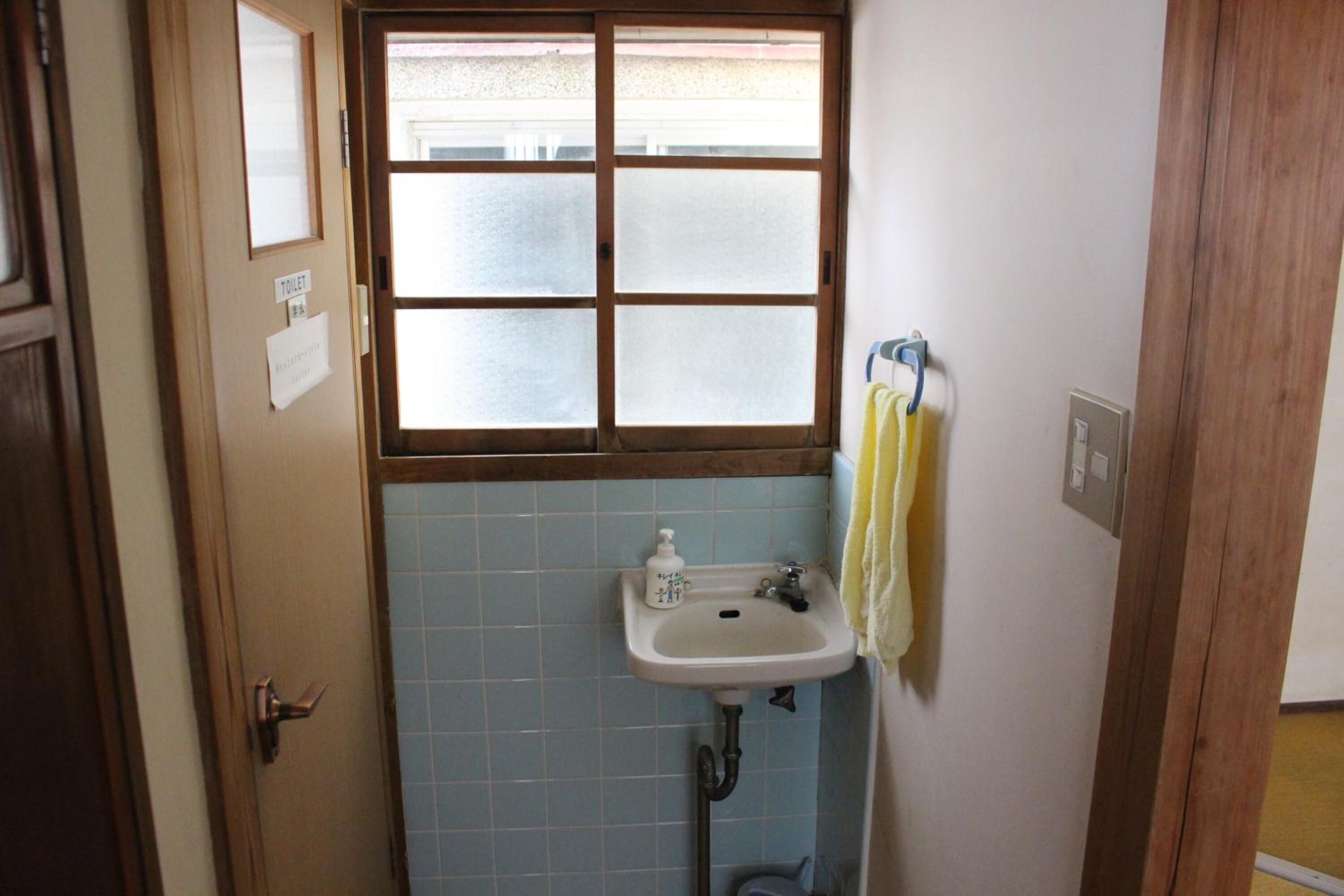 Un baño con ventana, lavamanos y una toalla colgada en la pared.