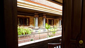 A traditional building with a tiled roof, columns, and a balcony with plants. - Segara Sadhu Inn Kuta by ecommerceloka (Kuta)