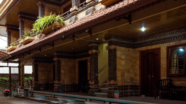 A traditional building with a covered porch, stone columns, and a tiled roof. - Segara Sadhu Inn Kuta by ecommerceloka (Kuta)