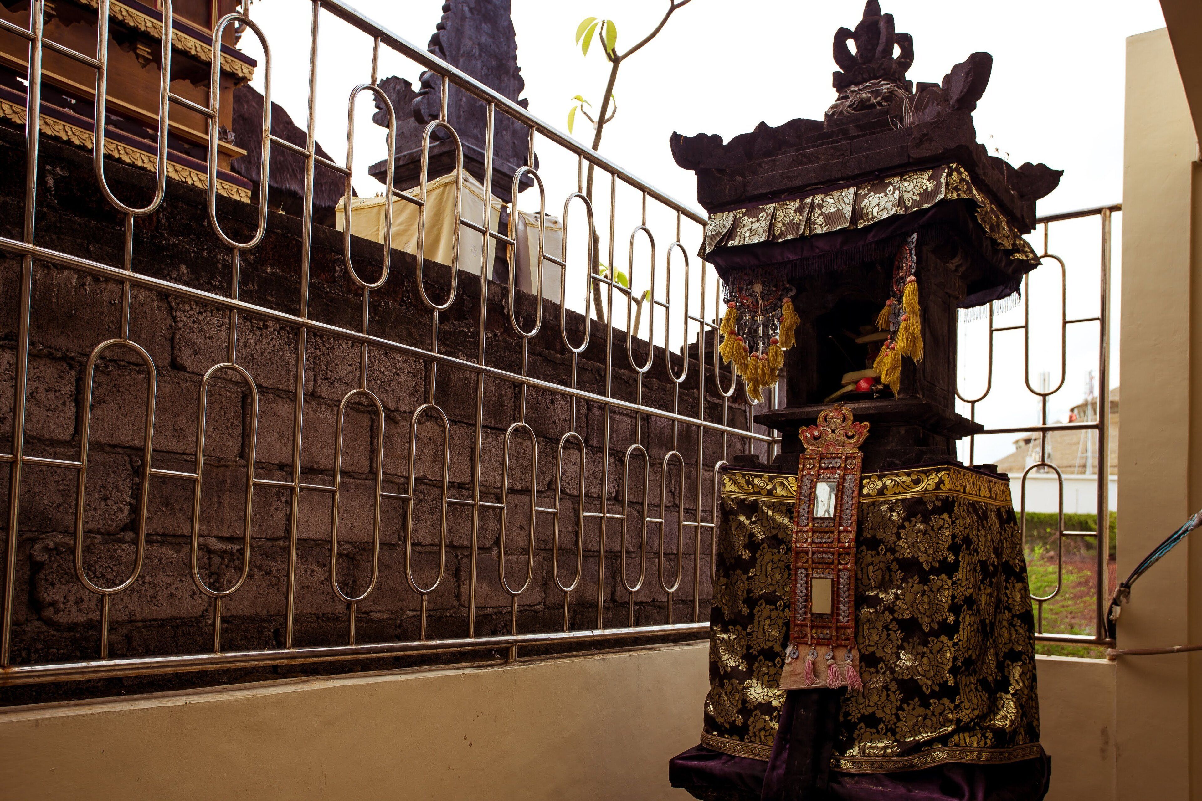 A traditional structure with ornate decorations and a metal fence in the background.