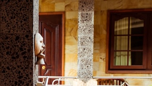 A stone facade with a carved face, a wooden door, and a window with curtains. - Segara Sadhu Inn Kuta by ecommerceloka (Kuta)