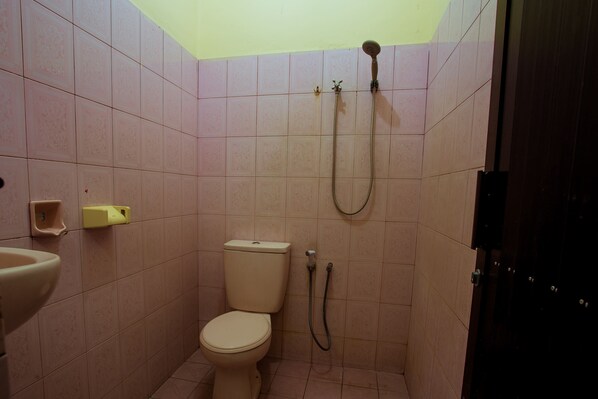 A small bathroom with a toilet, a sink, and a shower. - Segara Sadhu Inn Kuta by ecommerceloka (Kuta)