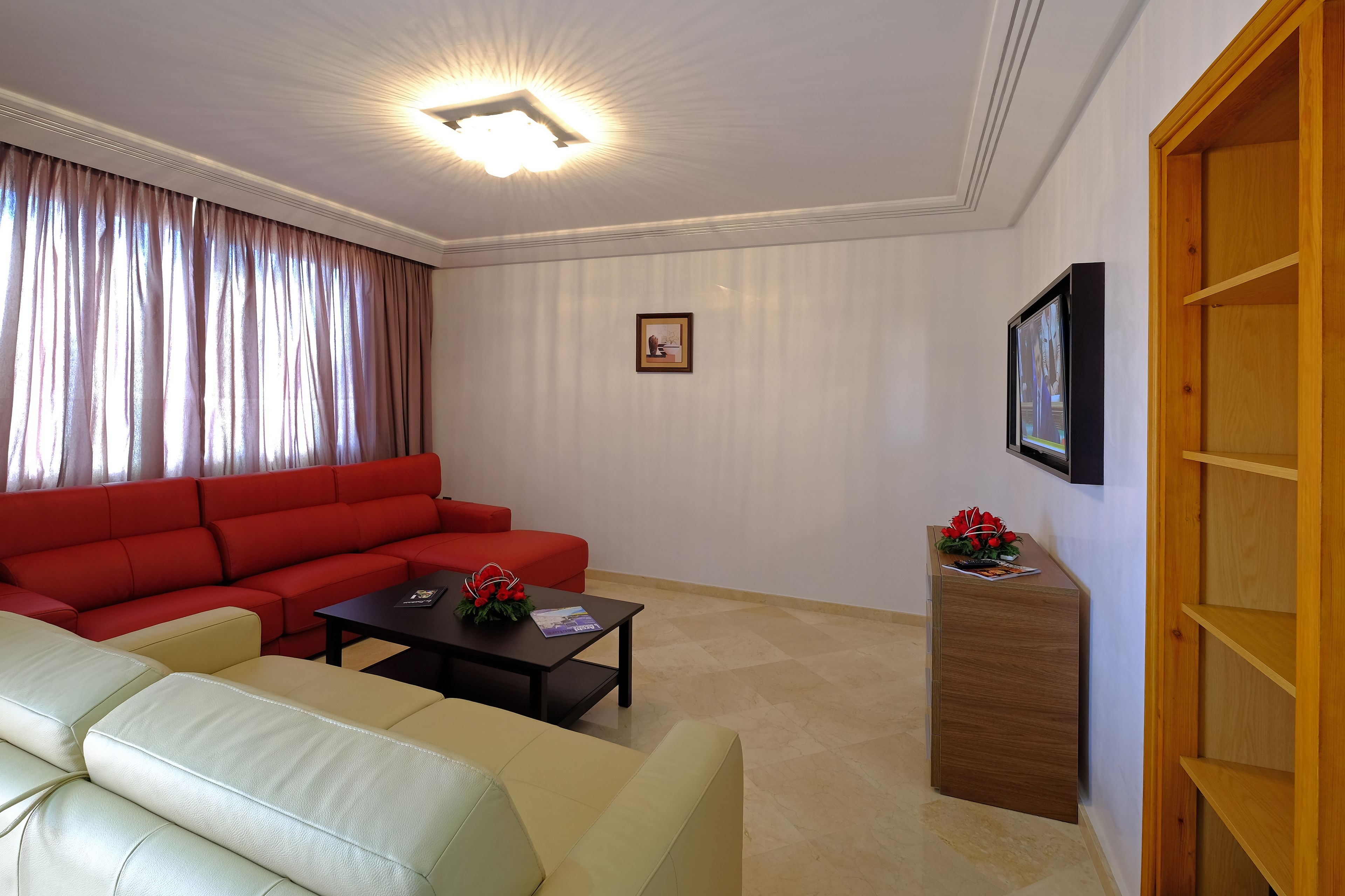 A living room with a red sectional sofa, a beige sofa, a coffee table, and a wooden sideboard.