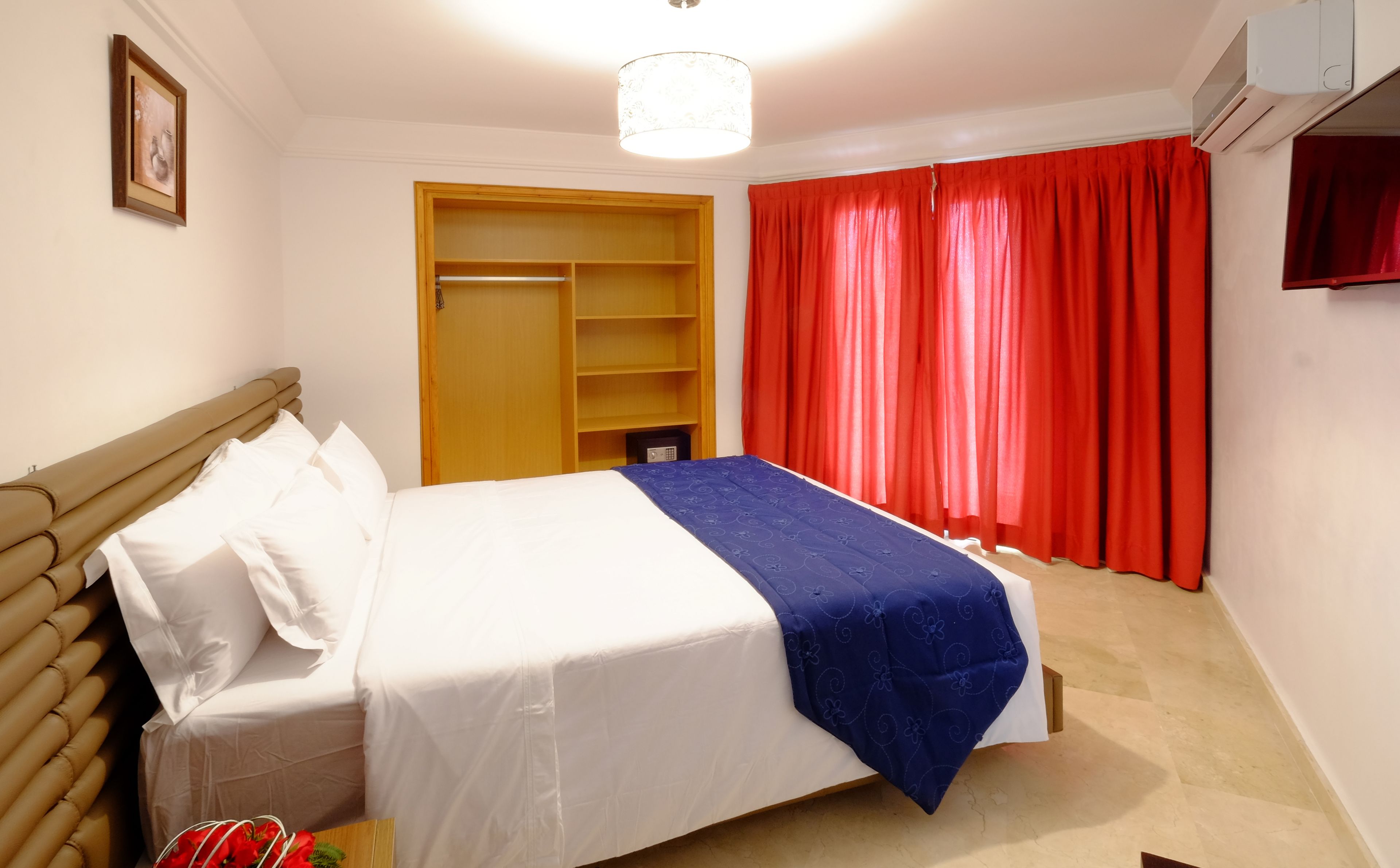 Ein Schlafzimmer mit Bett, Kleiderschrank und einem roten Vorhang.