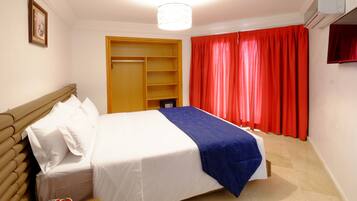 Un dormitorio con cama, armario y cortina roja.