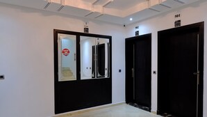 Un pasillo con tres puertas, una lámpara en el techo y un diseño en el suelo.
