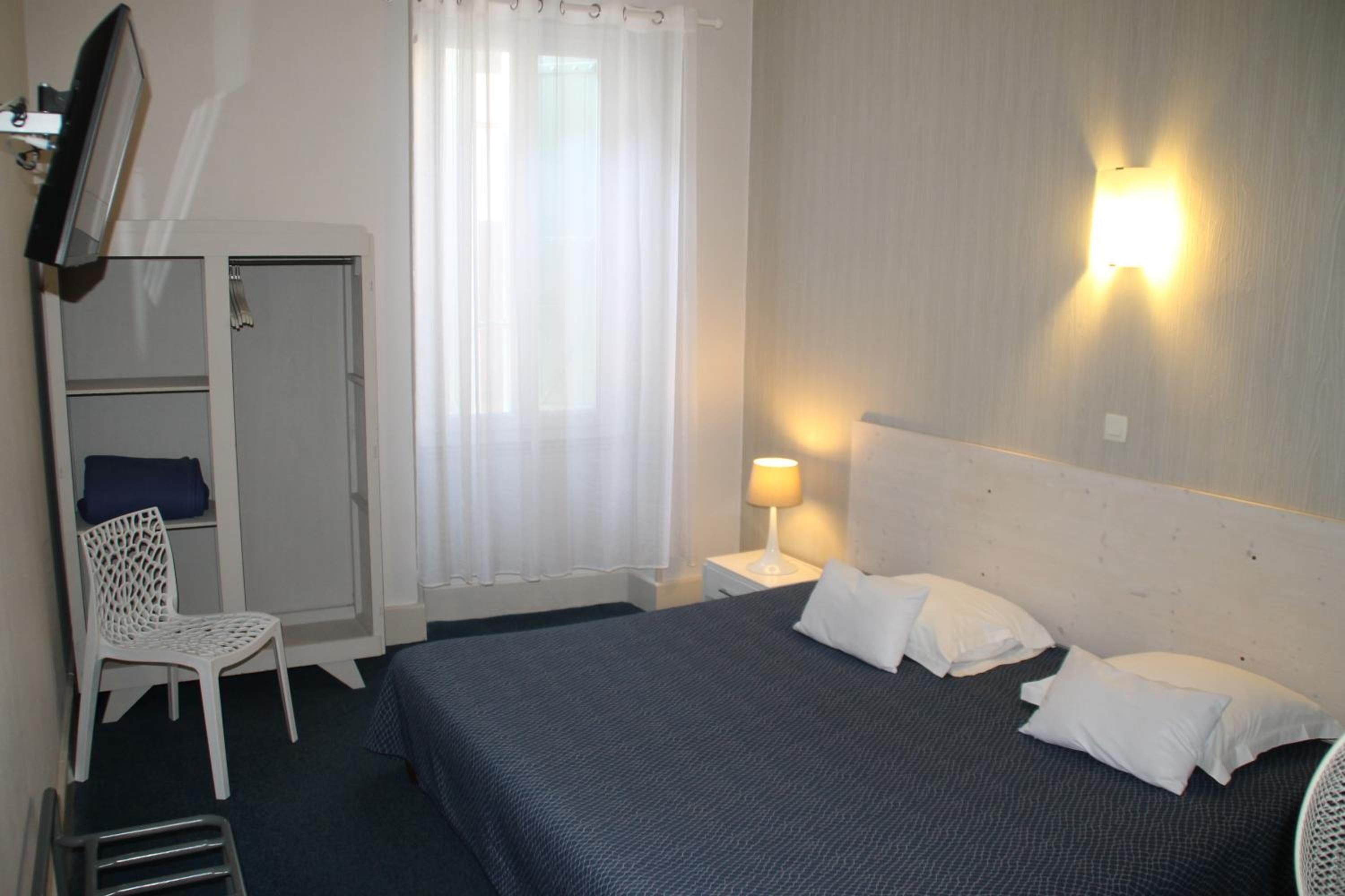 Une chambre d’hôtel comprenant un lit, une chaise, un bureau, une armoire et un téléviseur.
