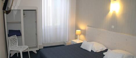 Une chambre d’hôtel comprenant un lit, une chaise, un bureau, une armoire et un téléviseur.
