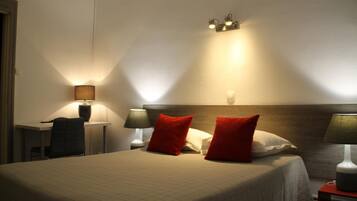 Ein Hotelzimmer mit einem Bett, zwei Nachttischlampen, einem Schreibtisch mit Stuhl und einer Wandleuchte.