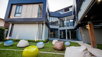 A modern building with a flat roof, large windows, and a well-maintained lawn with colorful bean bags.