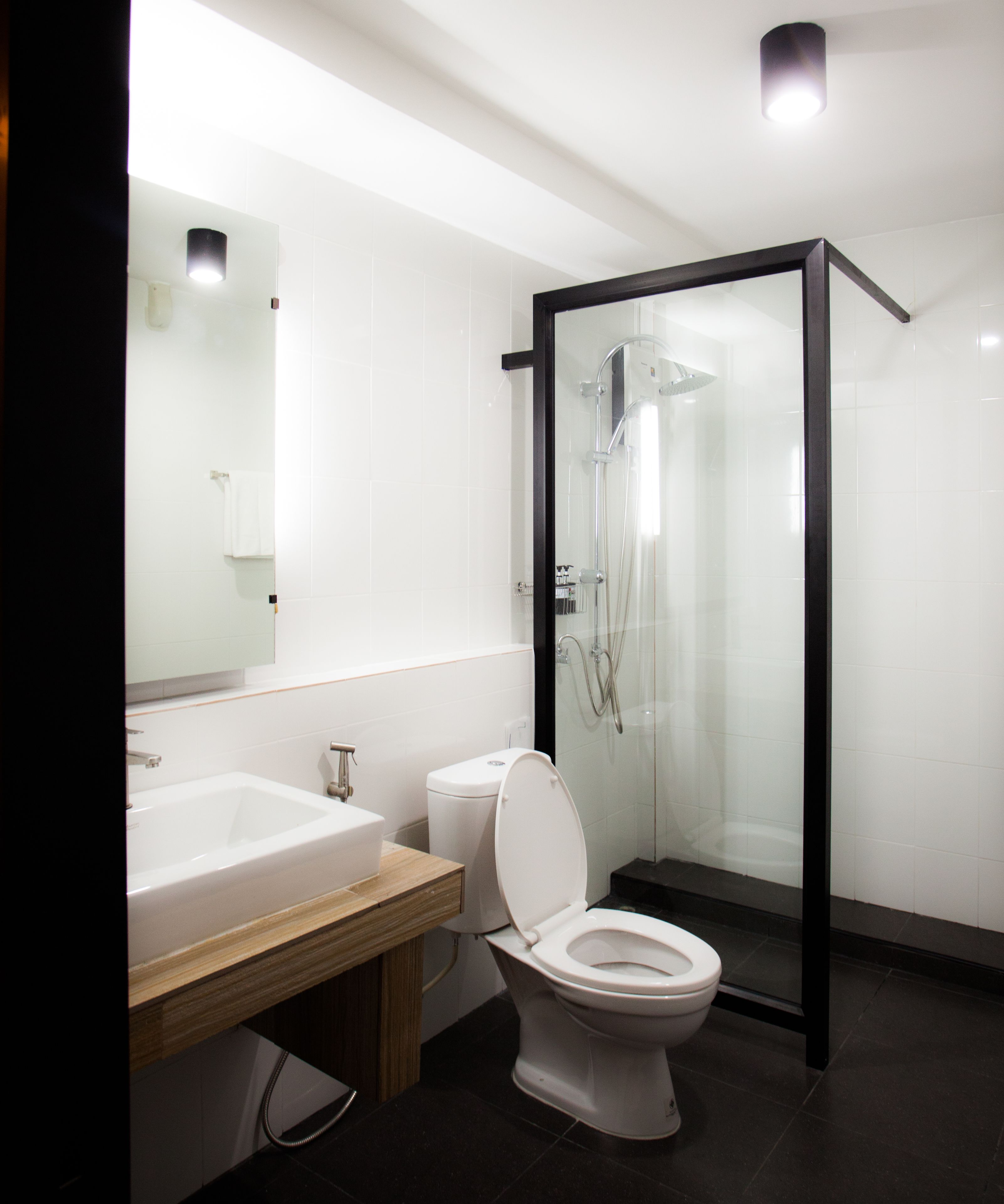 A modern bathroom with a glass-enclosed shower, a white sink, and a toilet.