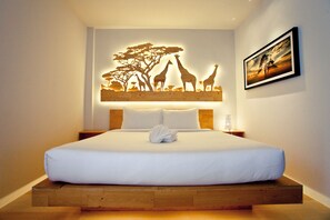 A neatly made bed with white linens, a wooden headboard, and a wall-mounted artwork depicting giraffes and trees. - My Room by Sermsub (Aranyaprathet)