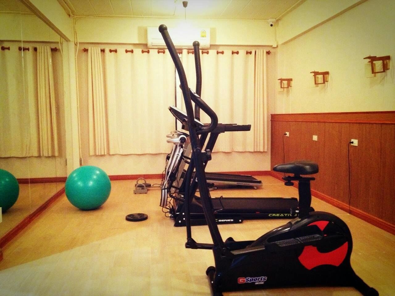 Un gimnasio con equipo de ejercicio, incluyendo una bicicleta estática, elíptica y cinta de correr.