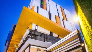 Un edificio moderno con fachada de vidrio, un alero amarillo y una entrada visible.