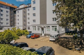 A multi-story residential building with a parking area in front.