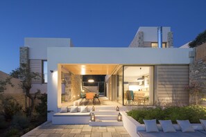 A modern house with a patio area featuring outdoor seating and a staircase leading to the entrance. - Atrium Villas (Skiathos)