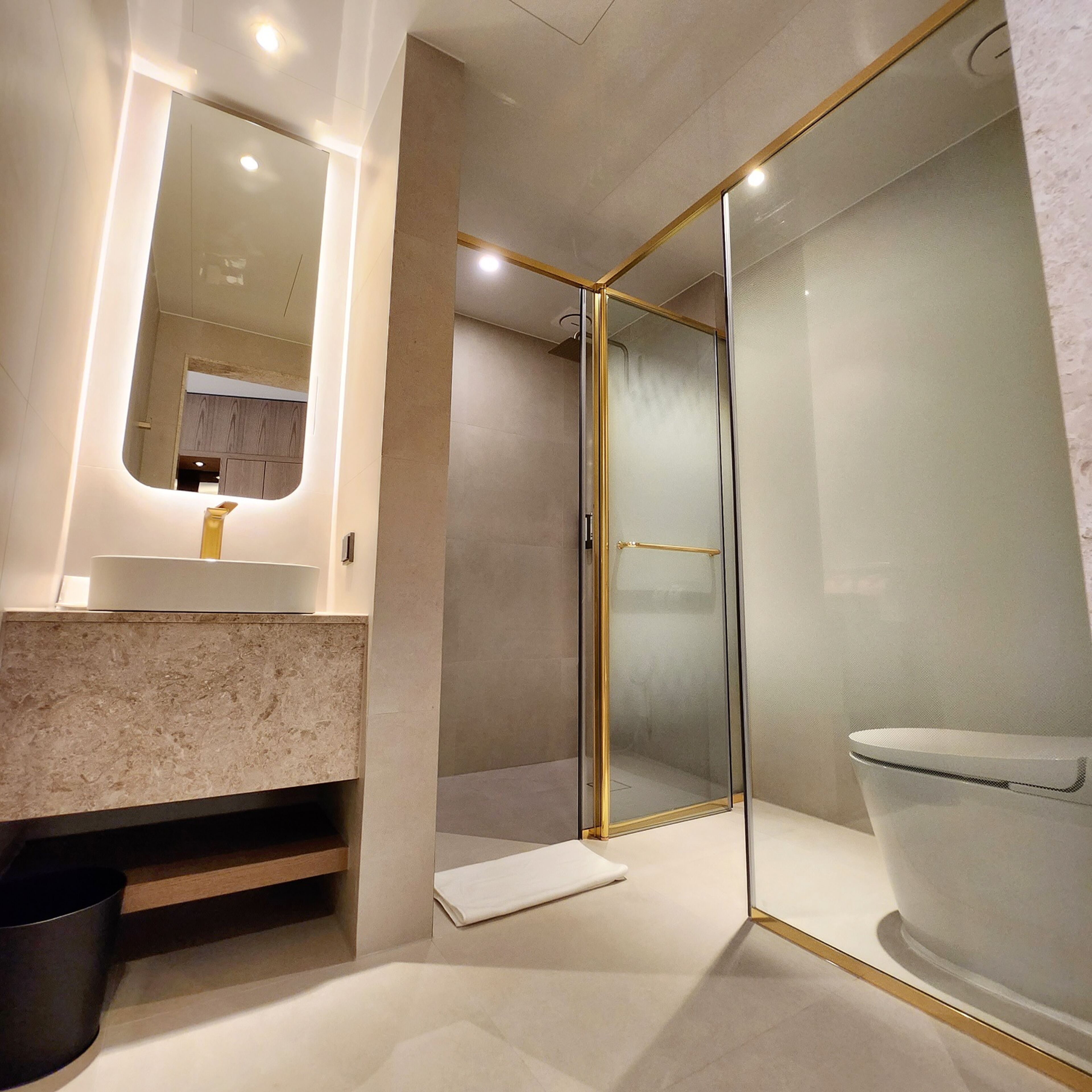 Une salle de bain moderne avec une douche à parois de verre, un lavabo en marbre et des toilettes.