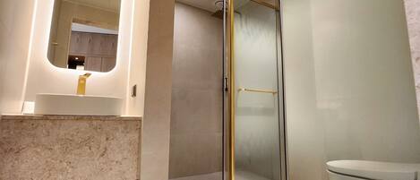 Une salle de bain moderne avec une douche à parois de verre, un lavabo en marbre et des toilettes.