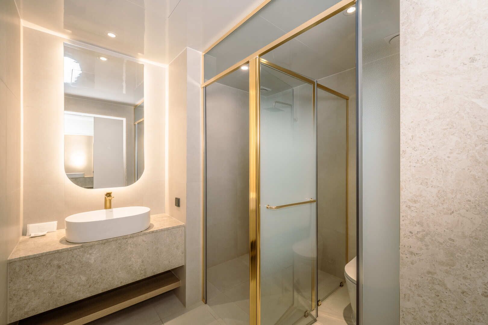 A modern bathroom with a freestanding white sink, a large mirror, and a glass-enclosed shower.
