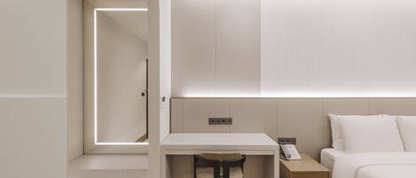 Habitación de hotel moderna con diseño minimalista, que incluye una cama, un escritorio con silla, una mesita de noche y un panel en la pared.